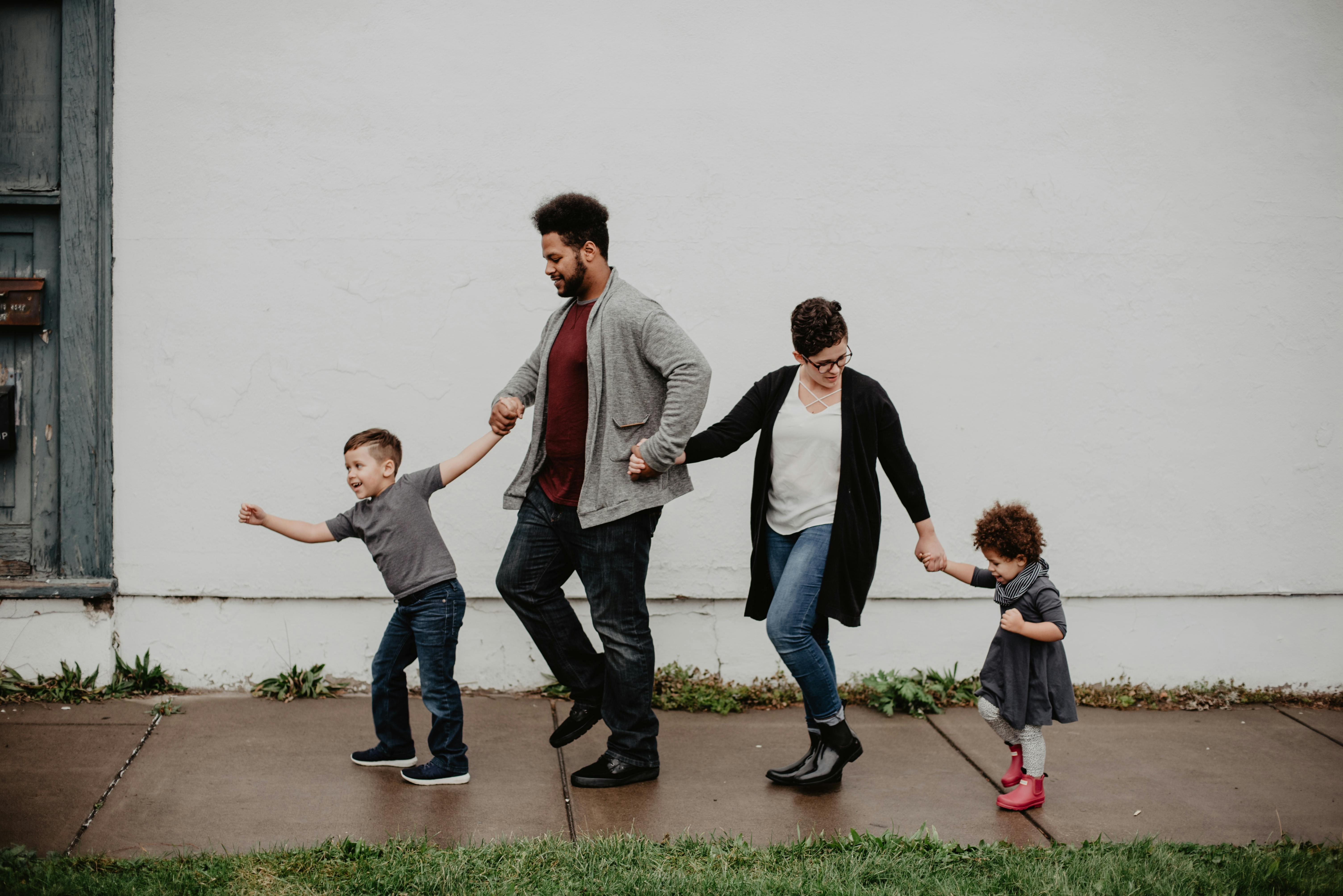 Family of four walking down sidewalk holding hands