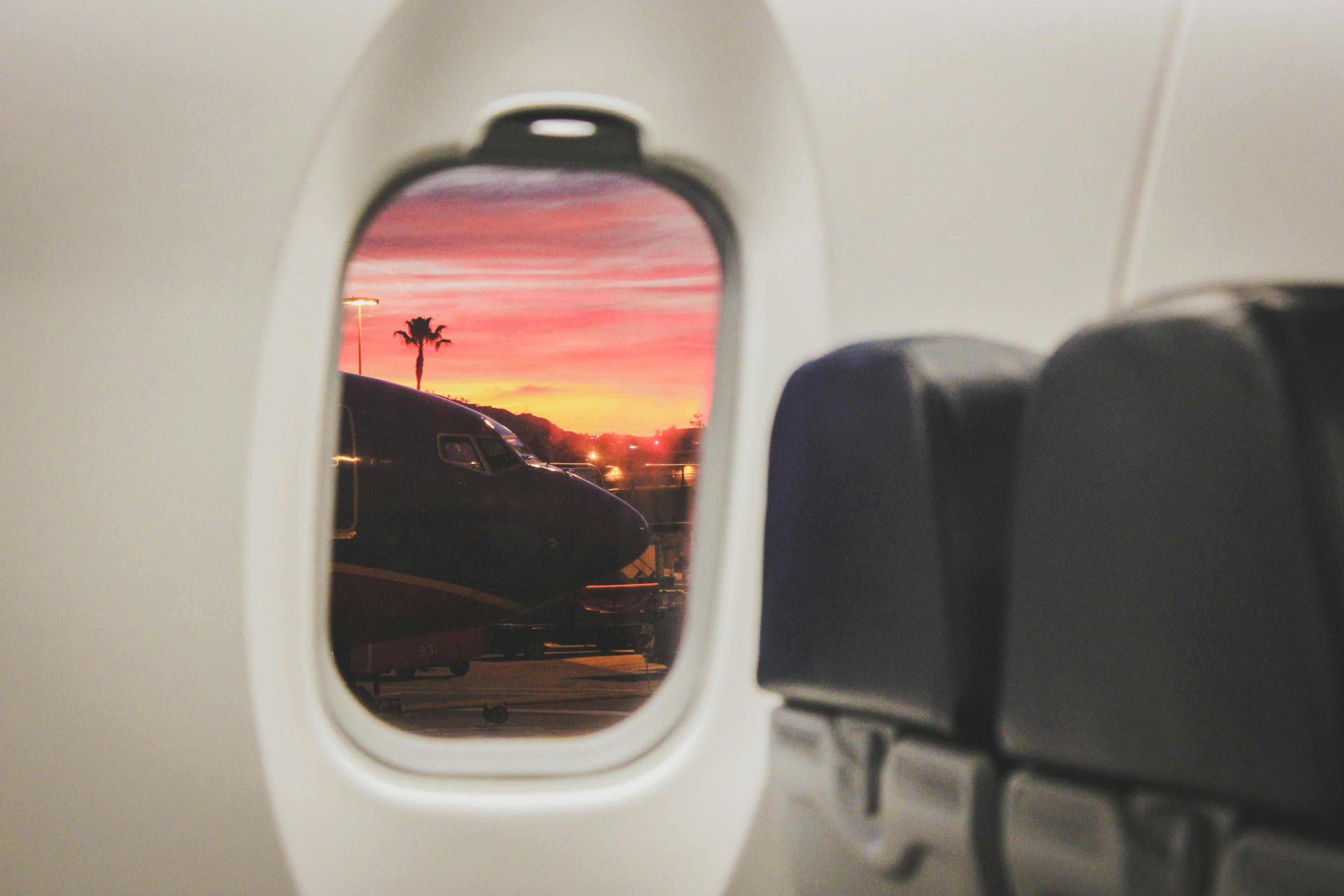 Airplane window looking out to sunset and palm trees